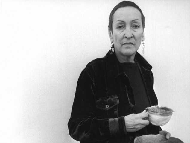 Meret Oppenheim 1975 mit Tasse und Teller mit Pelz überzogen und einem Kohlenobjekt (picture alliance : dpa).jpg
